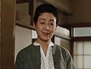 Interior shot of a middle-aged Japanese woman in modern clothes, smiling at the camera