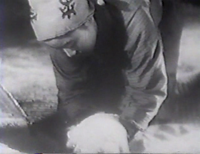 A young girl in peasant outfit crouching down and letting a handful of rice slide through her fingers