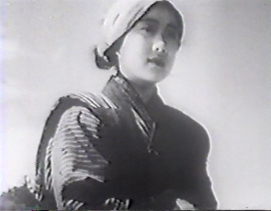 An adolescent girl, Otsugi, standing on a beach, looks off wistfully in the distance