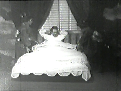 Photo of a Japanese man in nightclothes in a luxurious bed, being tended on either side by female servants