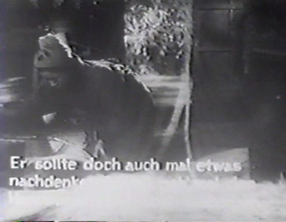 A shot of the film with the girl Otsugi on the ground, with white German subtitles against a white background