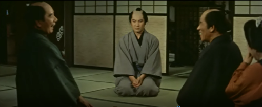 A sad young man sits in a room while two older men laugh at him in an 18th Century Japanese brothel