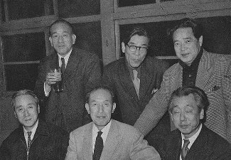 Six middle-age Japanese men in suits, three of them seated, the other three standing behind them.