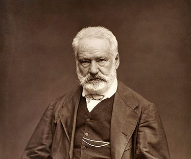 A portrait of an old bearded man, Victor Hugo, seated, and looking unsmiling at the camera
