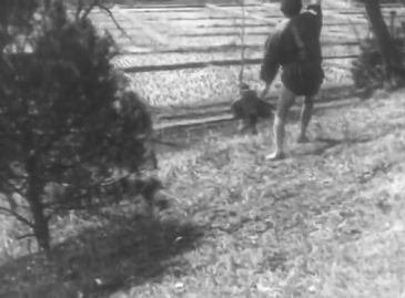 A rural landscape in which one man in feudal clothes appears in the foreground, and another in the background, both running away from the camera