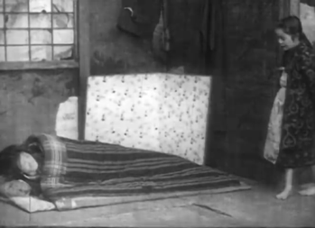 The room of a poor family in contemporary (1920s) Japan, in which the mother lies sick on the floor while a little girl watches