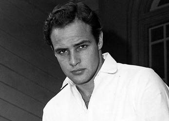 Studio portrait of Marlon Brando, ca. mid-1950s, in a white shirt staring at the camera