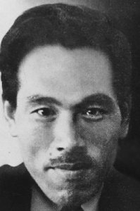 Old photo of a modern Japanese man with dark hair and a mustache, staring directly into the camera