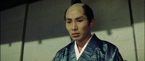 A Japanese man in feudal garb with the distinctive shaved forelock of a samurai looks worriedly into space