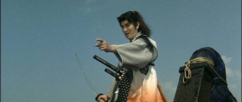 A young samurai on a ship, in elaborate garb and shoulder-length hair, points to something in front of him