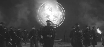 The Japanese man dressed as a ninja appears in the foreground with his large, similarly-dressed men around him, while the firework burns in the background