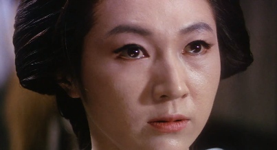 The face of a Japanese women with a hairdo from the feudal era, looking somberly at something outside of the frame