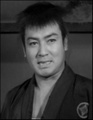 A thirtyish Japanese man in common feudal clothing, with unkempt hair, looks at something slightly to the side of the frame 