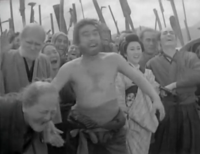 The archer in the earlier pictures, now shirtless, and surrounded by a crowd, laughs at something beyond the range of the camera 