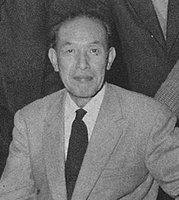 Photo of a middle-aged Japanese man, facing the camera and wearing a business suit, ca. mid-1950s